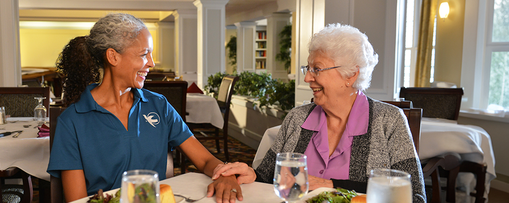 A Visiting Angels caregiver and an elderly woman sharing a joyful moment together, highlighting the importance of companionship in care services.