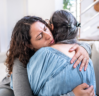 Adult female child hugs her senior mother.