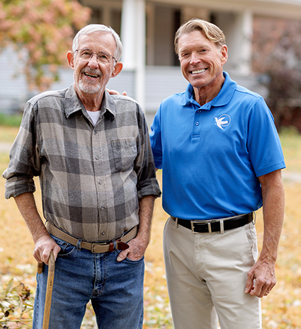 A male Visiting Angel standing next to an elderly man.